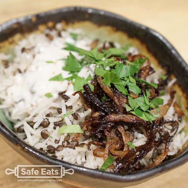 Photo of a bowl of mujardara rice and lentils with crispy onions and milk-free yogurt sauce.
